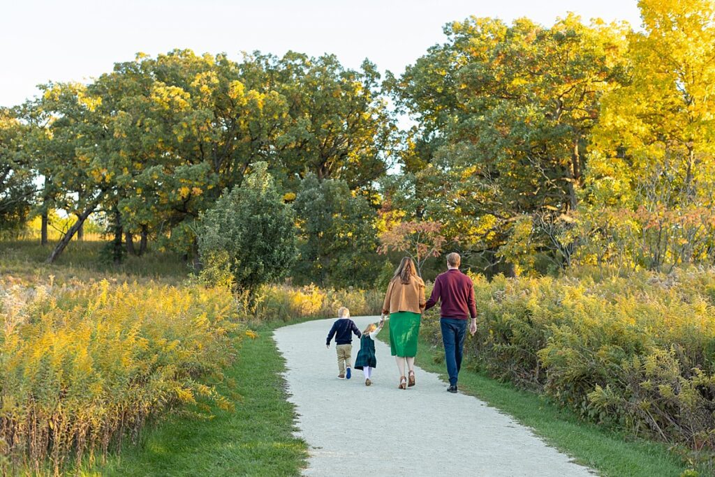 Hinsdale family photographer, family of four walking a gravel path with trees and green/golden brush
