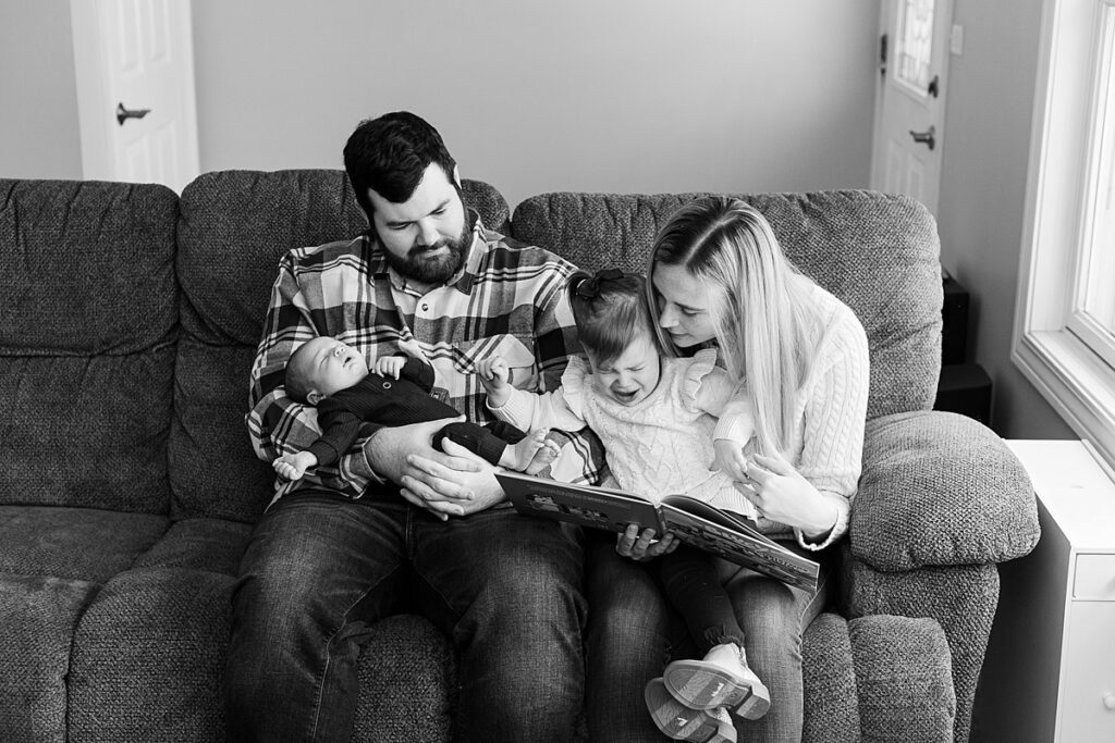 black and white photo of family of four reading a book during a newborn session, Lisle Newborn Photographer