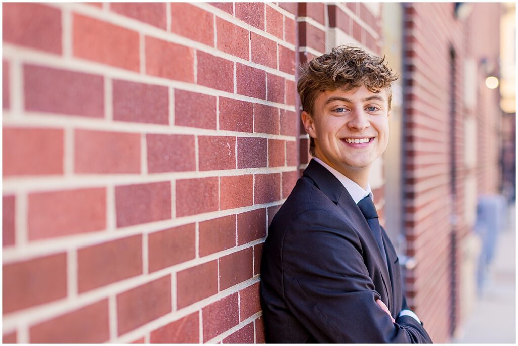 Senior Photographer, senior against red brick wall photos