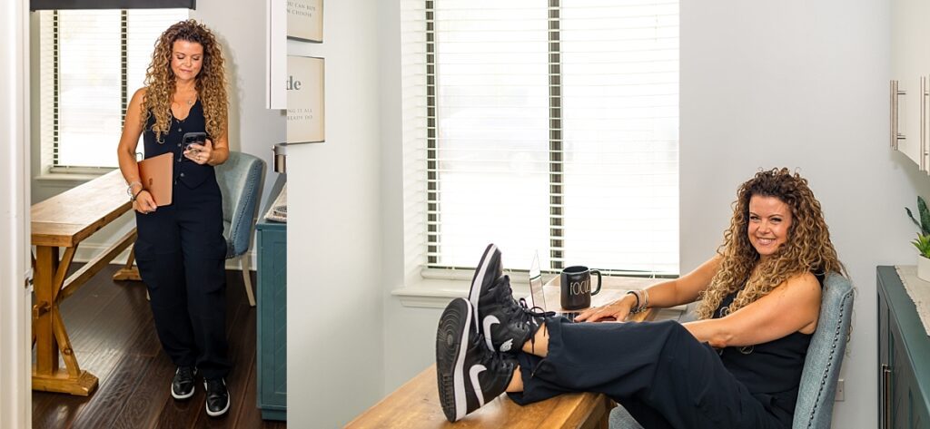 curly haired woman in black jumpsuit running her business in her office with computer and cell phone