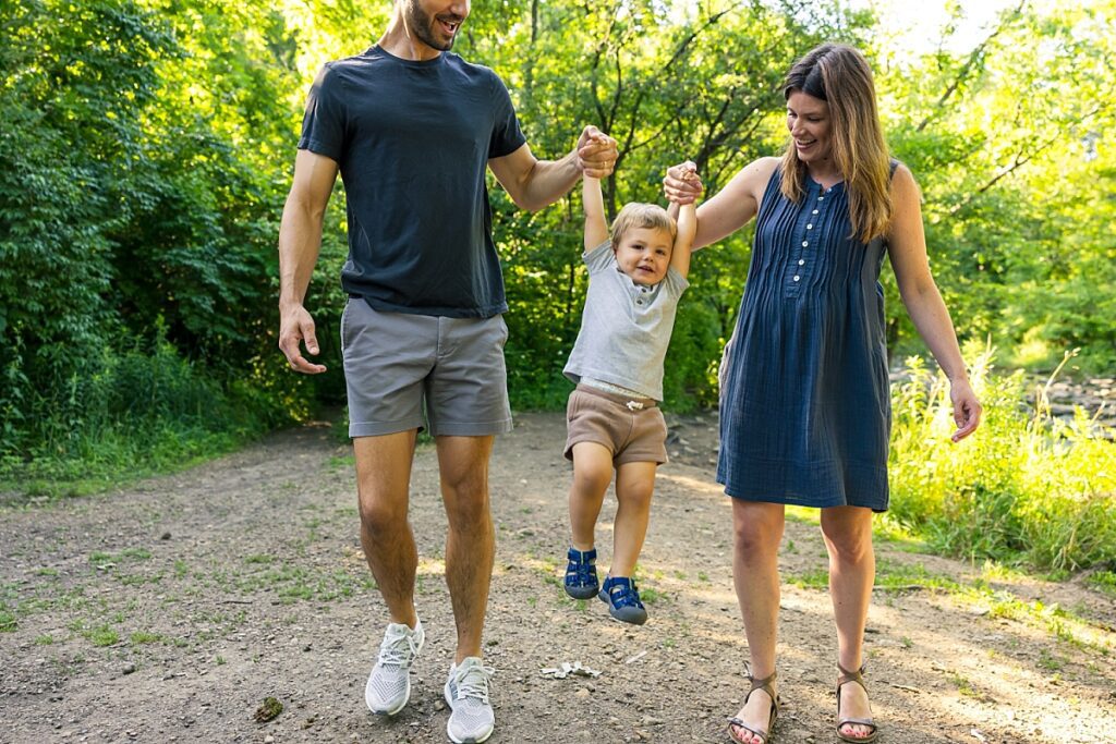 mom and dad swinging toddler boy at a maternity session before baby sister arrives