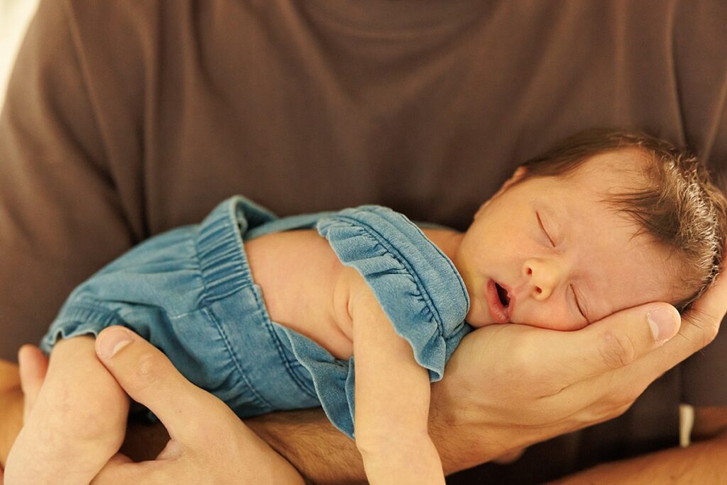 Newborn girl laying on dad's arm 