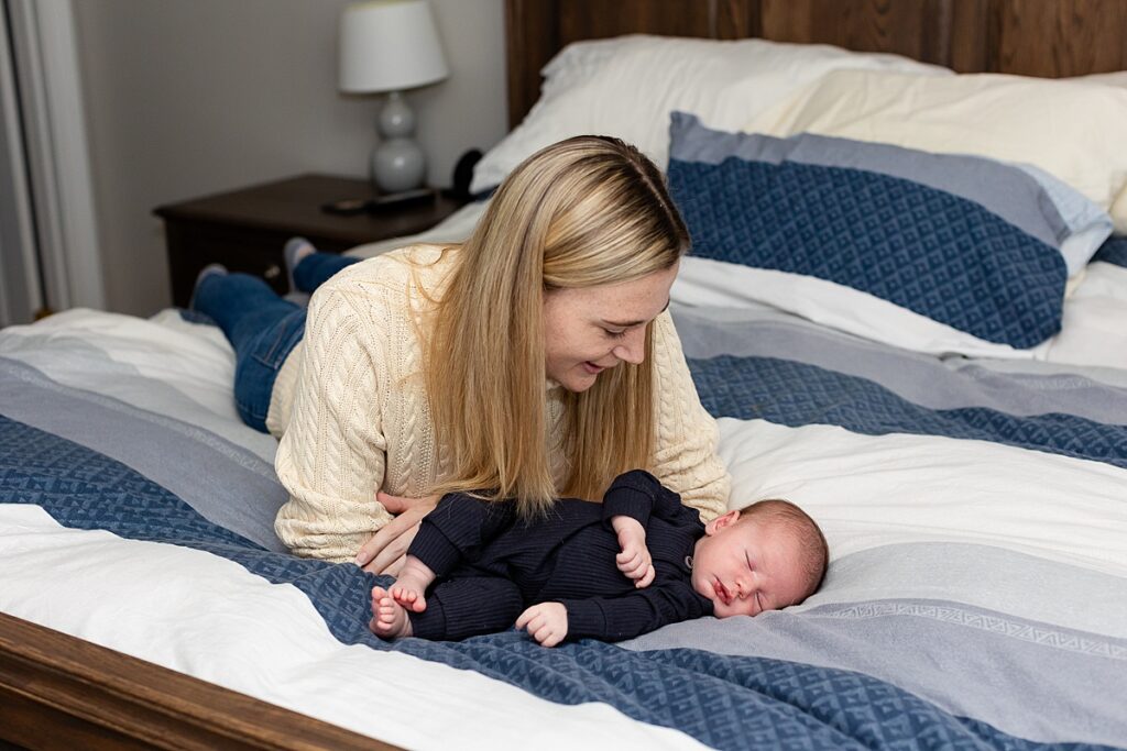 mom and newborn laying on bed during a newborn session